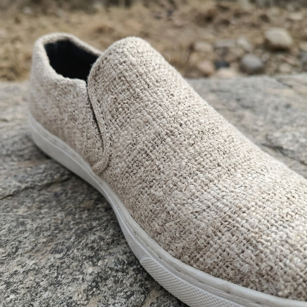 Beige pure hemp slip-on shoe with white bio degradable rubber sole on a stone surface