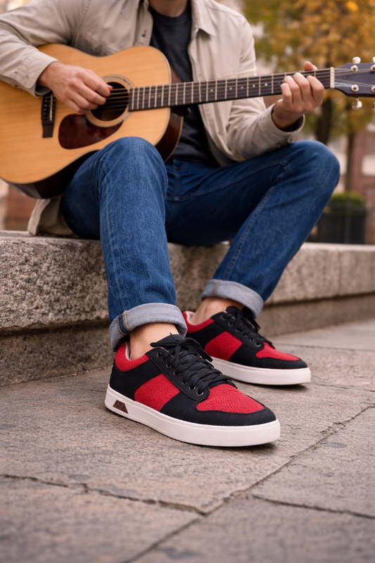 Person playing guitar with a focus on red and black sneakers