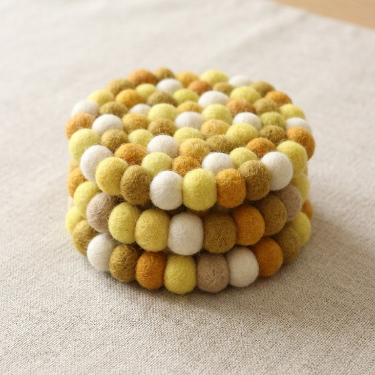 Stack of Mustard Yellow wool felt coasters handmade in Nepal, warm absorbent non-scratch drink coasters for wooden tables, teacher gifts, host gifts and new home buyers on a textured surface