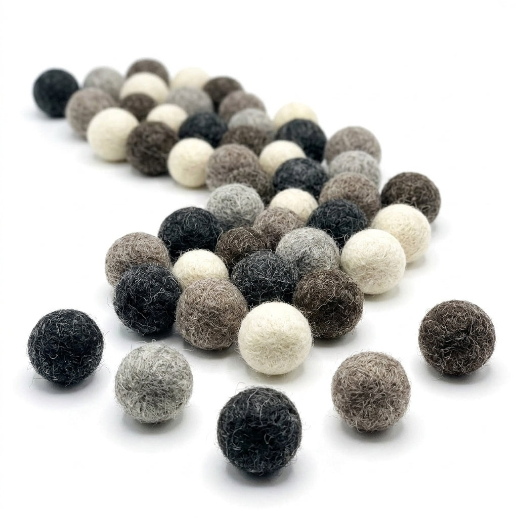 Assorted black,white and gray felt balls for crafts and diy projects on a white background