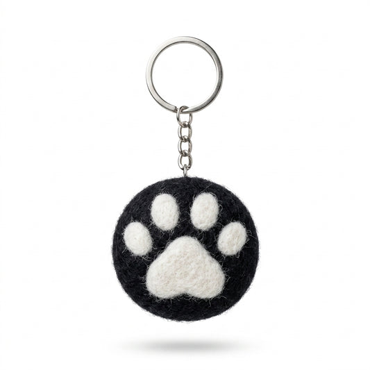 Black wool felt cat paw keyring with white paw print with a paw print design on a white background