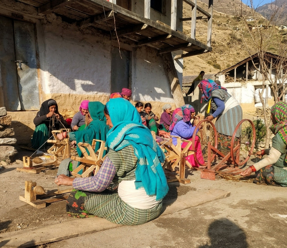 Group of women spinning hemp yarn using manual spinning wheels in a mountainous village setting.