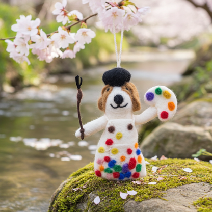 Handmade wool felt painter dog ornament  on a rock with cherry blossoms in the background