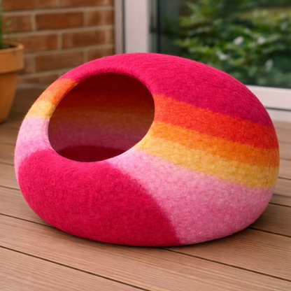 Colorful striped pet bed on a wooden surface with a blurred outdoor background