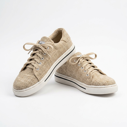 Pair of natural beige organic hemp canvas lace-up shoes with beige laces, white natural rubber soles and a thin black stripe on a plain white background.

