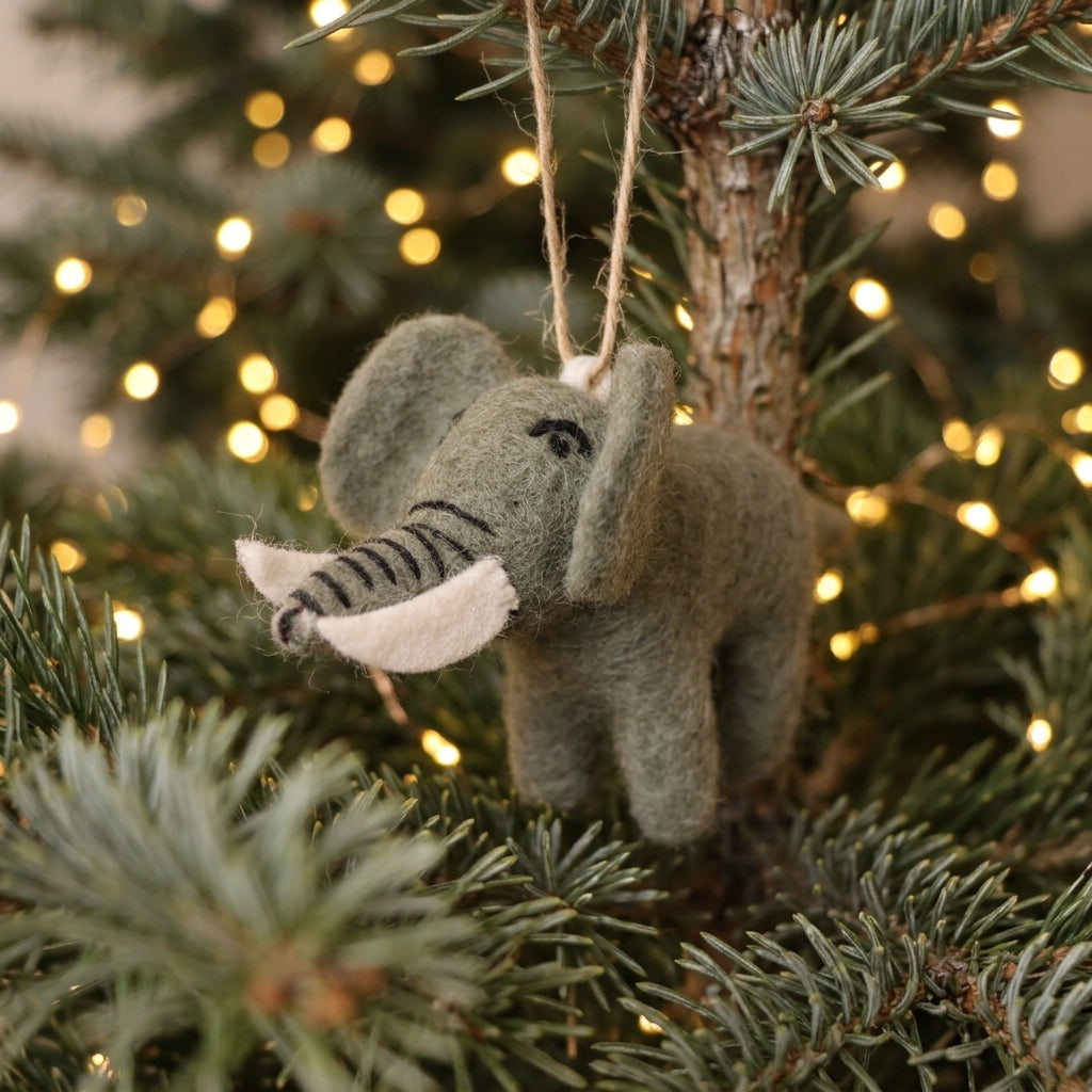 Felt elephant ornament hanging on a Christmas tree with lights in the background