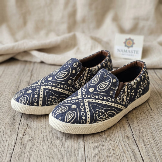 Pair of blue patterned handmade hemp shoes on a wooden surface with a beige fabric background.